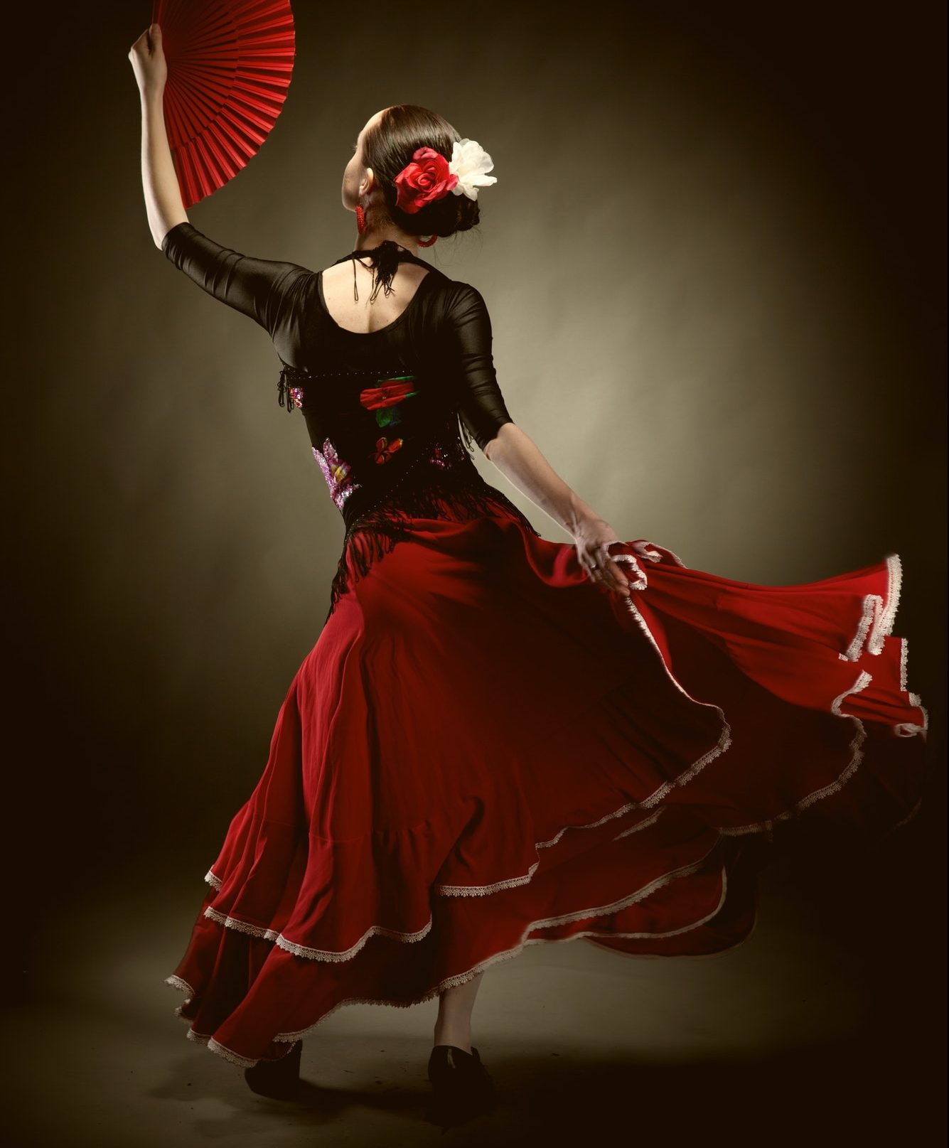 young woman dancing flamenco on black